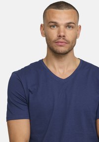 T-shirt bleu marine à col en V, à manches courtes, en coton doux, avec une texture lisse et une coupe ajustée. Uni, sans motifs ni accents.