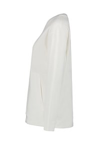 Camiseta blanca de manga larga con cuello redondo y bolsillos laterales. Textura suave, corte relajado y tela ligera.