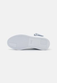 White sneaker sole with a textured bottom, featuring a clean design and slight cushioning. Includes a label near the heel.
