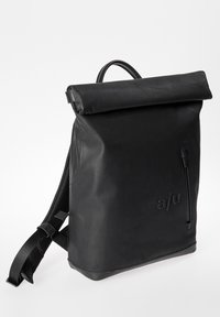 Zaino roll-top nero realizzato in materiale liscio e opaco. Presenta una tasca con zip sul lato e spallacci regolabili e imbottiti per il comfort.