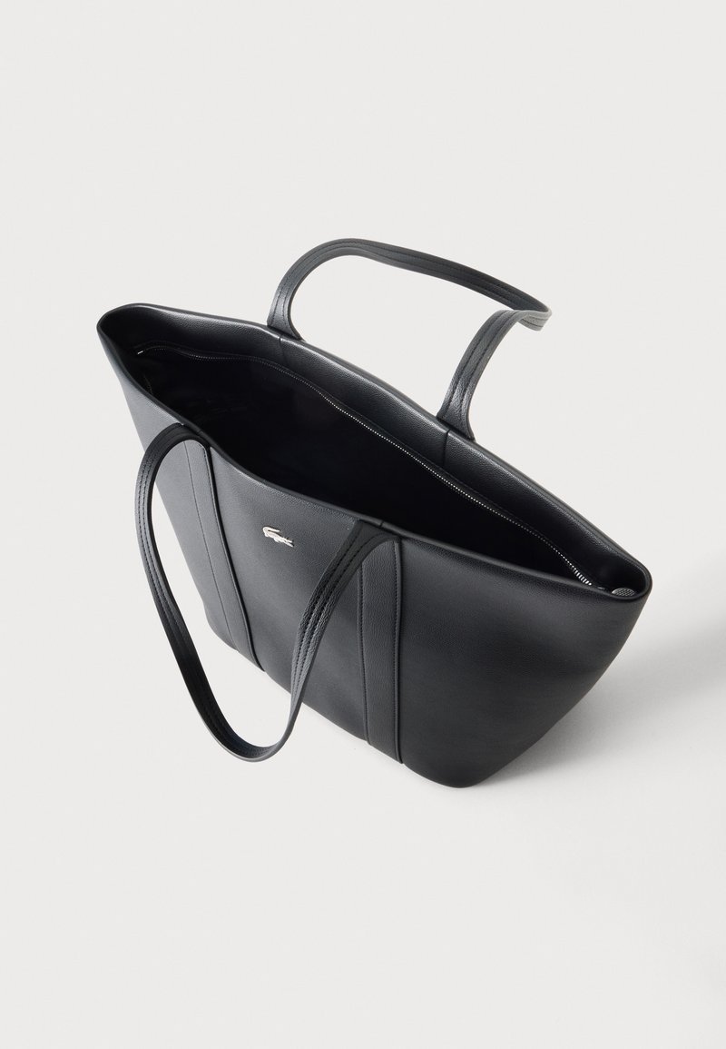 Borsa tote in pelle nera con doppi manici e piccolo logo argentato sul davanti, mostrata aperta su uno sfondo chiaro uniforme.