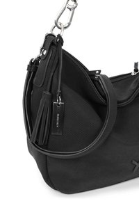 Schwarze Schultertasche mit strukturierter Oberfläche, ausgestattet mit einem glatten Tragegurt, einem Quastenelement und einem Metalletikett. Der Reißverschluss ist teilweise sichtbar.