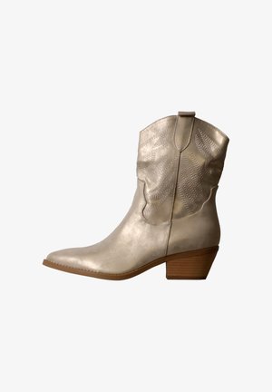 Botte de cowboy en cuir beige clair avec motifs d'ailes cousus, bout pointu, languette de traction et talon en bois empilé sur fond blanc.