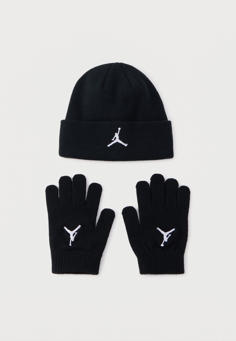 Črna pletena kapa z belim logotipom Jumpman spredaj, v kombinaciji s črnimi rokavicami s tem istim logotipom na vsakem zapestju.