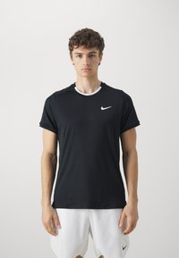 Svart trenings t-skjorte med rund halsutskjæring, korte ermer og en hvit Nike-logo på øvre venstre bryst. Glatt stoff.