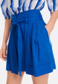 Blaue Leinen-Shorts mit weitem Bein, hohem Bund und gebundenem Gürtel. Verfügt über seitliche Taschen und einen umgeschlagenen Saum.