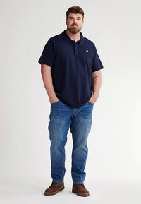 Tmavě modré polokošile s límečkem, krátkými rukávy a malým logem. Kombinováno s světle modrými džíny a hnědými botami, s pohodlným střihem.