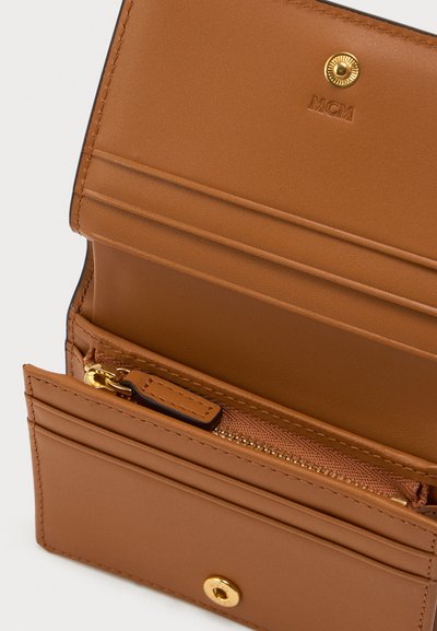 Tan leren portemonnee met meerdere kaartsleuven, een ritsvak en een gouden drukknoopsluiting. Heeft een reliëfmerk op de binnenkant.