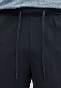 Sorte atletiske shorts med en struktureret stof, udstyret med en taljebånd med eksterne snore og et minimalistisk design.