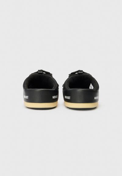 Chaussons noirs rembourrés avec un design texturé, dotés d'une semelle contrastante en tan et d'une marque au talon. Design minimaliste, style à enfiler.