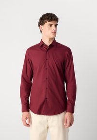 Burgunderfarbenes Langarmhemd mit schwarzen Knöpfen, klassischem Kragen und tailliertem Design. Glatte Textur mit einem leicht glänzenden Finish.