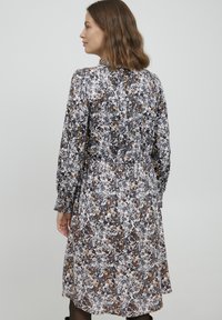 Rochie cu imprimeu floral, cu mâneci lungi, talie strânsă, tonuri de gri, alb și portocaliu, având o silueta fluidă și detalii adunate în spate.
