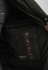 Fodera interna del giubbotto verde, idrorepellente, con sezione antivento, caratterizzata da icone etichettate e un termometro. Logo Gabbiano presente.