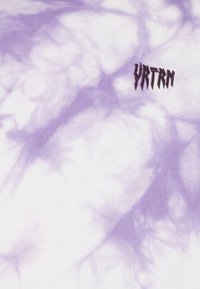 Tissu tie-dye violet et blanc avec un petit texte noir indiquant "YRTRN" dans une police stylisée en forme de dents en haut à droite.
