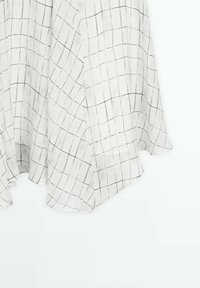 Tissu blanc à motif de grille noire, suspendu avec de doux plis et un bord légèrement courbé en bas.
