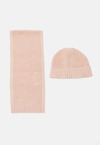 Knitted pink hat and scarf set. The hat has a ribbed brim and textured pattern. The scarf features a similar texture with ribbed edges.