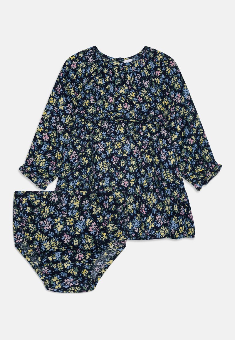 Cvetna obleka in ujemajoči se krojni hlačnici v mornarsko modri barvi z živahnim večbarvnim vzorcem. Narejena iz lahkotnega materiala, z dolgimi rokavi in zbranim pasom.