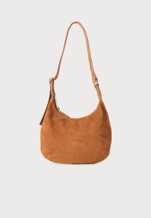 Borsa a spalla in suede color tan con design curvo, tracolla regolabile, zip in metallo e dettaglio con logo embossato sul frontale.