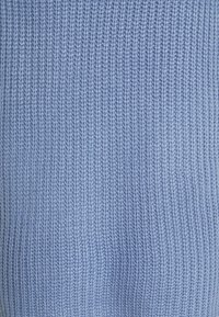 Tissu bleu clair tricoté avec une texture côtelée, présentant des lignes verticales régulièrement espacées. Aspect doux et tissage uniforme.