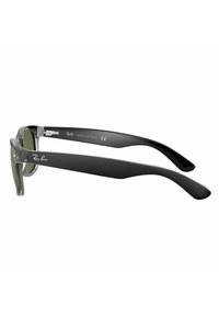 Occhiali da sole con montatura trasparente grigia e lenti verde scuro, bracci neri e dettagli silver. Presentano il logo Ray-Ban sul braccio. Made in Italy.