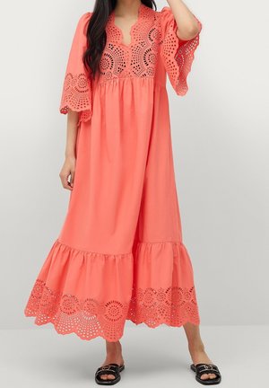 Robe maxi couleur corail avec un motif en dentelle ajourée sur les manches et l'ourlet. Le tissu est léger, présentant une coupe décontractée et une jupe évasée.