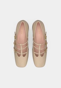 Beige ballerinatossor med flera horisontella remmar, rund tå, mjukt material och guldfärgade detaljer. Innersulan har en rosa nyans.