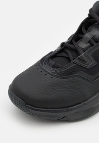 Czarny but sportowy z połączeniem teksturowanej skóry i siateczki, wyściełanym kołnierzem oraz gumową podeszwą z detalem bieżnika.