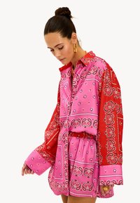 Langarmshirt in levendig rood en roze met paisleypatroon. Lichtgewicht stof, met kraagontwerp en een comfortabele pasvorm.