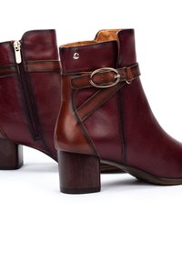 Bottines en cuir bordeaux avec une sangle en cuir marron et une boucle en argent. Comprend une fermeture éclair sur le côté et un talon en bois.