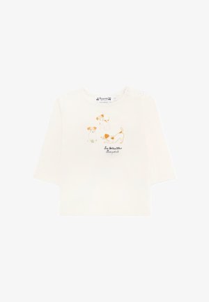 Camicia a maniche lunghe di colore crema chiaro, realizzata in cotone, con tre illustrazioni di cani in marrone e arancione e il testo "Les Petites Babanes" sottostante.