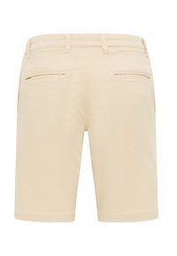 Shorts beiges avec une texture douce, dotés de deux poches arrière et sans matériel visible, conçus pour un usage décontracté.