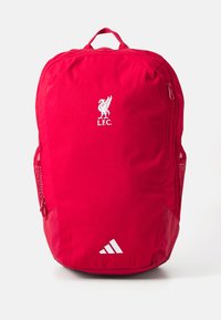 Red backpack made of fabric, featuring a Liverpool FC logo in white, a side mesh pocket, and a bottom accent with three white stripes.