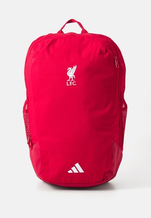 Rød ryggsekk laget av stoff, med Liverpool FC-logo i hvitt, en side mesh-lomme, og en bunnkant med tre hvite striper.