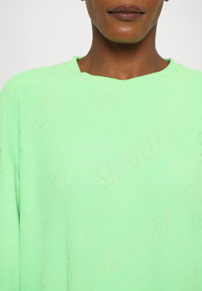 Maglione verde oversize realizzato in tessuto testurizzato, con scollatura rotonda e un discreto motivo a logo in rilievo sulla superficie.