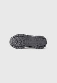 Black hiking shoe sole with a textured rubber grip, featuring a zigzag pattern and reinforced areas for durability.