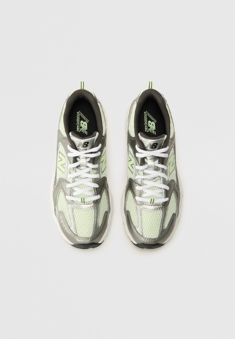 Baskets de course avec tige en mesh vert et gris, lacets blancs et accents noirs. Présente des panneaux texturés et un logo sur la languette.
