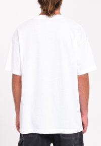 T-shirt en coton blanc à coupe décontractée, à manches courtes et col rond. Le dos est uni, sans motifs ni graphiques.