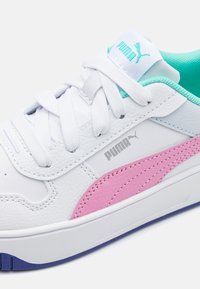 Sneaker bianche in pelle con accenti rosa e grigi, dotate di lacci bianchi, interno azzurro chiaro e logo in rilievo sul lato.