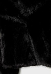 Tessuto in pelliccia artificiale nera con una consistenza morbida e densa. La superficie presenta lunghezze di pelliccia variabili, evidenziando un aspetto ricco e scuro.