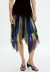 Pleated seel, millel on musta, sinise ja kollase värvi gradient. Alumine äär on asümmeetriline ja läbipaistev. Kombineeritud siniste rihmadega kontsaga kingadega.