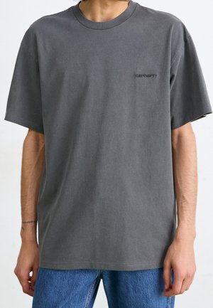 Graues Baumwoll-T-Shirt mit Rundhalsausschnitt und kurzen Ärmeln. Mit einem kleinen schwarzen Logo auf der linken Brust. Lockerer Schnitt, glatte Textur.