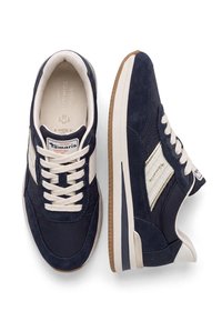Paire de baskets décontractées bleu marine et blanches avec lacets blancs, accents beiges et semelles en caoutchouc, vues de dessus et de côté.