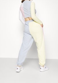 Lehký souprava na doma obsahující krátký, vícebarevný top s dlouhým rukávem a odpovídající tepláky s elastickým pasem a kapsami.