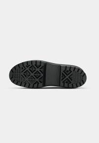 Suola di scarpa in gomma nera caratterizzata da un motivo di battistrada robusto con design geometrici per una maggiore aderenza e stabilità. Superficie texturizzata per una maggiore durata.