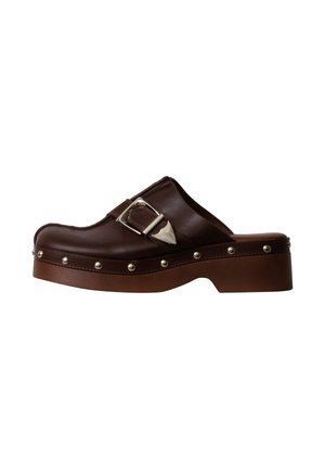 Sabot en cuir marron avec boucle argentée, bord clouté et semelle chunky, vue de côté sur fond blanc.