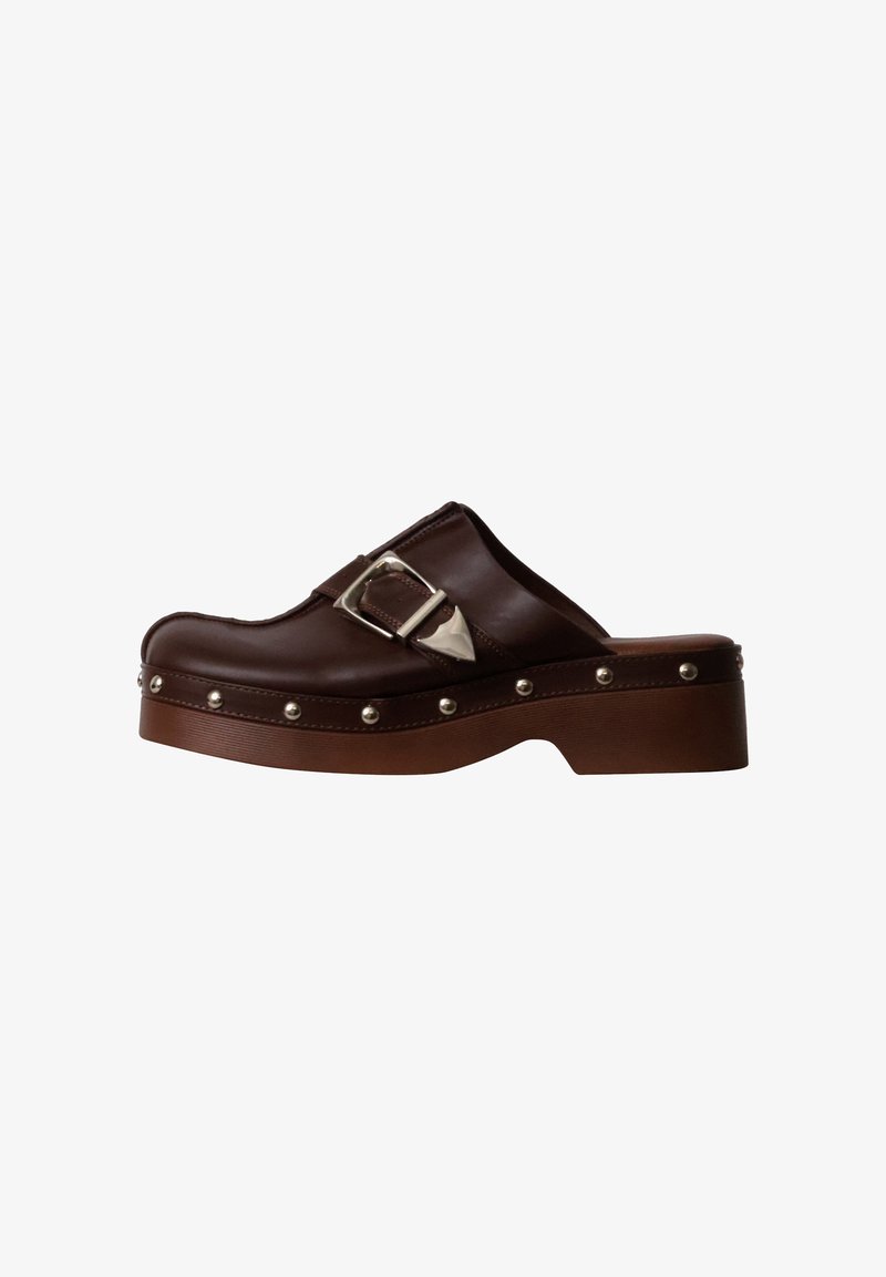 Sabot en cuir marron avec boucle argentée, bord clouté et semelle chunky, vue de côté sur fond blanc.