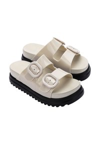 Białe gumowe klapki z dwiema regulowanymi paskami i okrągłymi klamrami, z grubą czarną podeszwą i gładką teksturowaną wkładką.