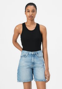 Top negro de canalé y pantalones cortos de mezclilla azul claros. Los pantalones cortos cuentan con una cintura alta y un corte recto con un cierre de botón.