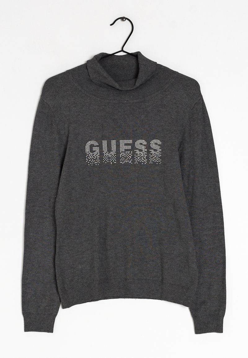 Grauer Strickpullover mit Rollkragen, auf der Vorderseite mit "GUESS" aus Strasssteinen verziert. Elastische Bündchen und Saum. Hängt an einem schwarzen Haken.