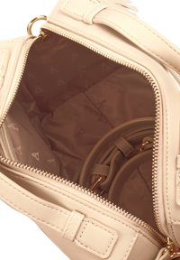 Beige laukku, joka on valmistettu synteettisestä materiaalista, varustettu vetoketjukiinnityksellä, sileällä ulkopinnalla ja vuoratulla sisällä, jossa on toistuva logokuosi.